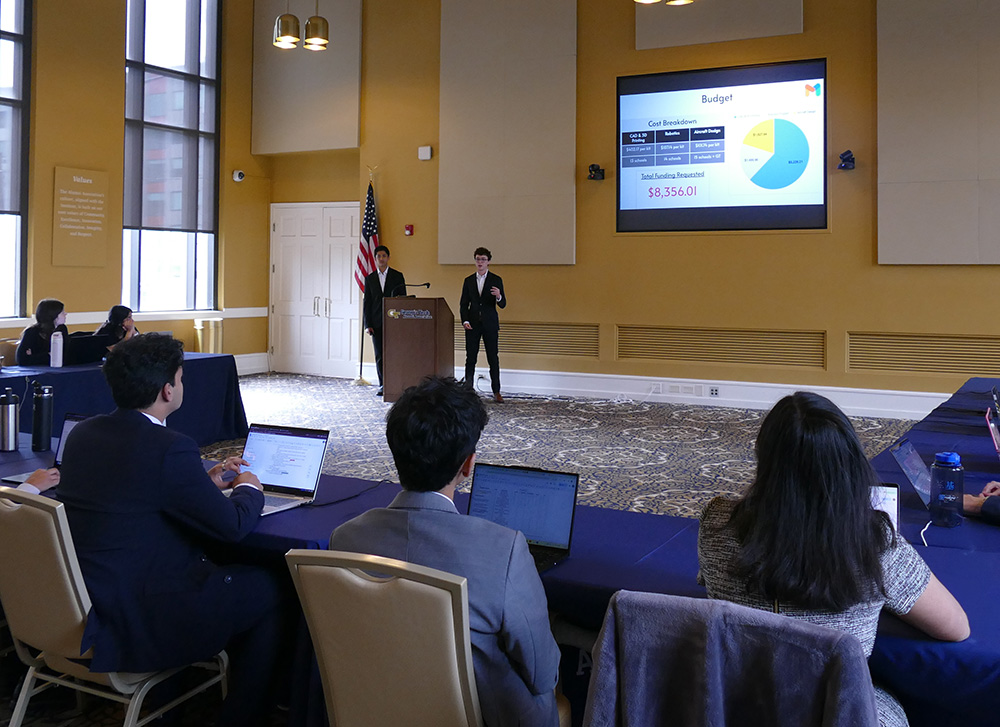 Two students presenting in front of a crowd