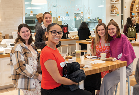 A group of alumnae are around a table at a restaurant. 