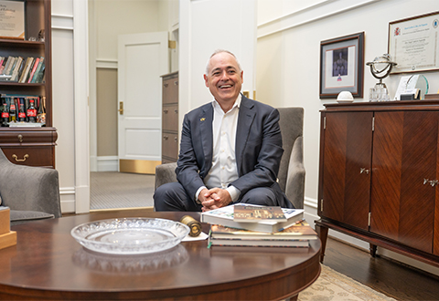 President Angel Cabrera sitting in his office on a couch smiling.