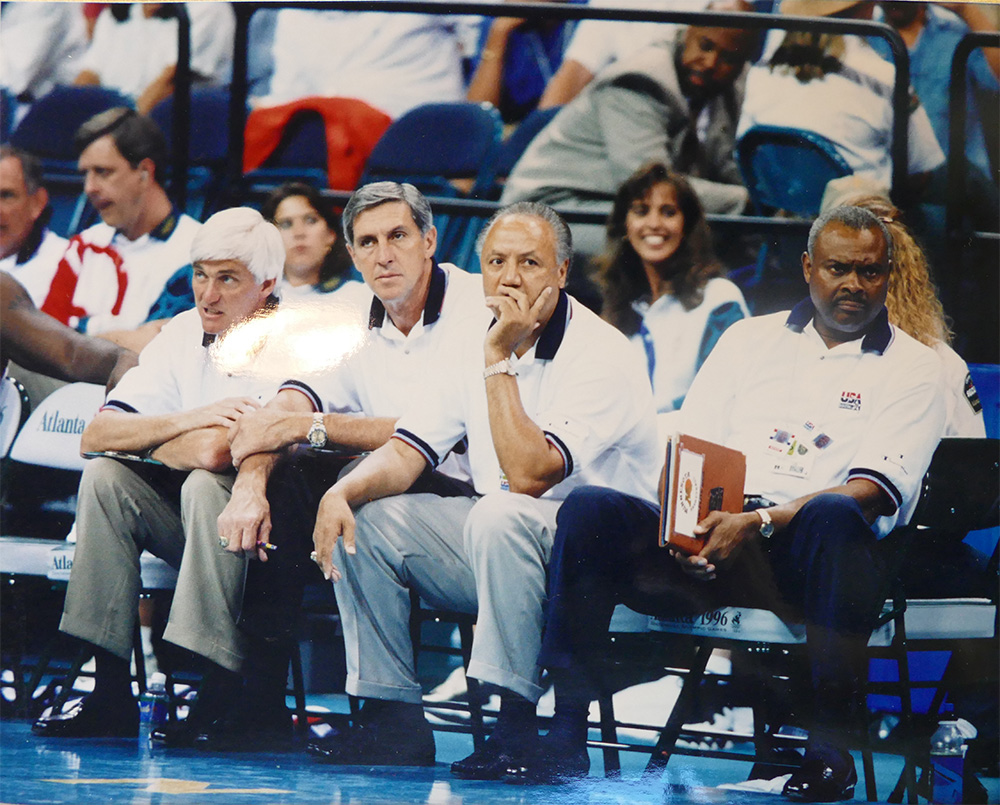 Coach cremins sitting on the bench with the rest of the coaching staff