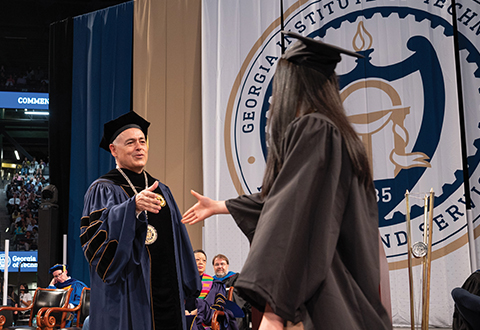 President Cabrera shaking a graduating student's hand on stage
