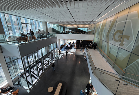 view looking down from a balcony above showing a modern and bright lobby area with the letters GT as a mural on the wall. 