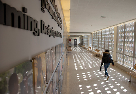A person with a backpack on walks through a hallway. 