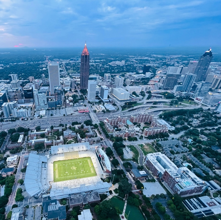 Aerial view of Bobby Dodd Stadium on the Georgia Tech campus surrounded by the Atlanta skyline at dusk.