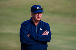 Bruce Helper on a golf course with his arms folded